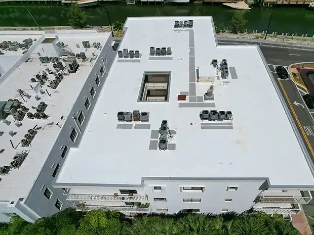 Aerial view of a waterfront building with a new white flat roof